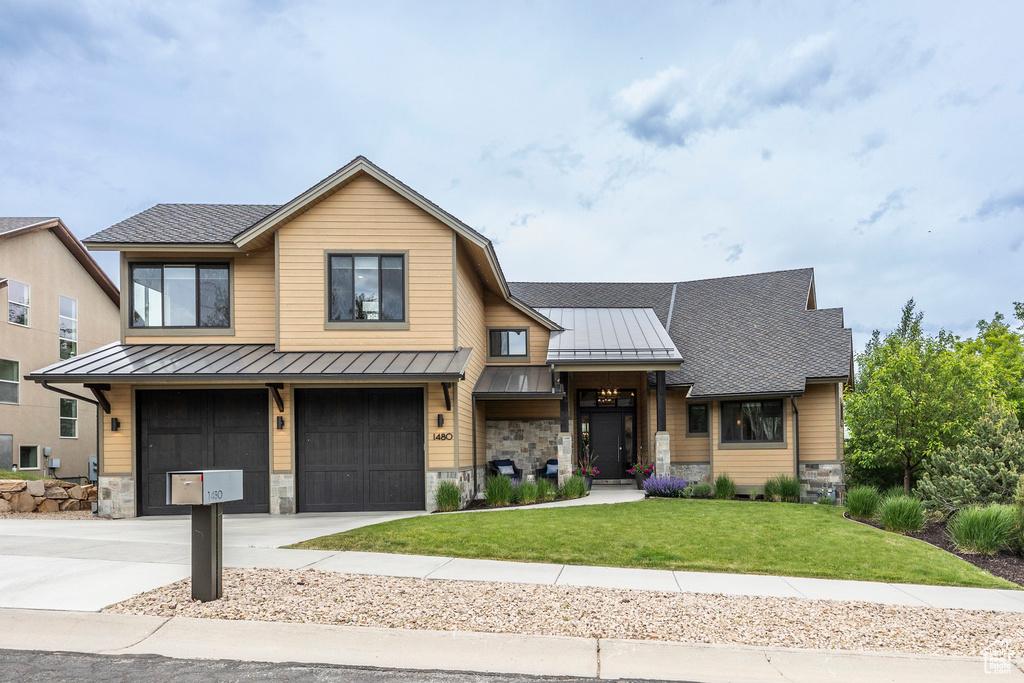 View of front of house featuring a standing seam roof, stone siding, and concrete driveway