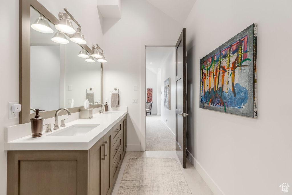 Bathroom with double vanity, tile patterned floors, and vaulted ceiling