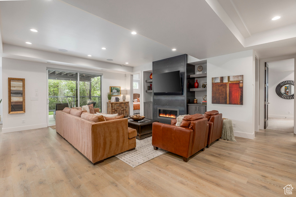 Living area featuring light wood-style flooring, a large fireplace, baseboards, and recessed lighting