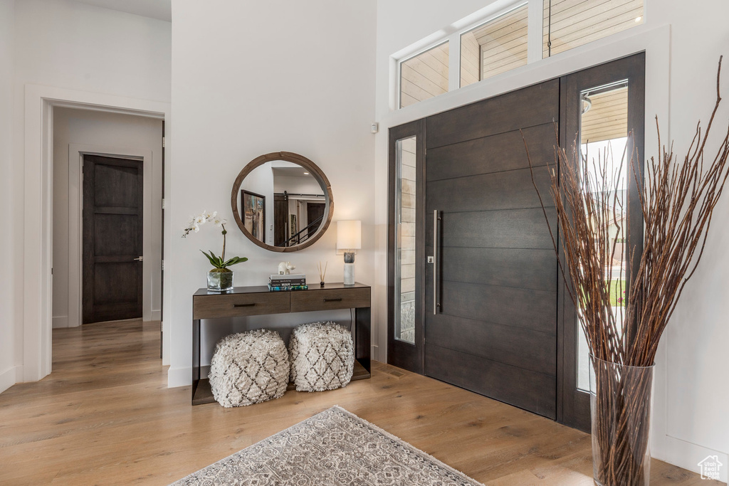 Foyer featuring wood finished floors, a towering ceiling, and baseboards