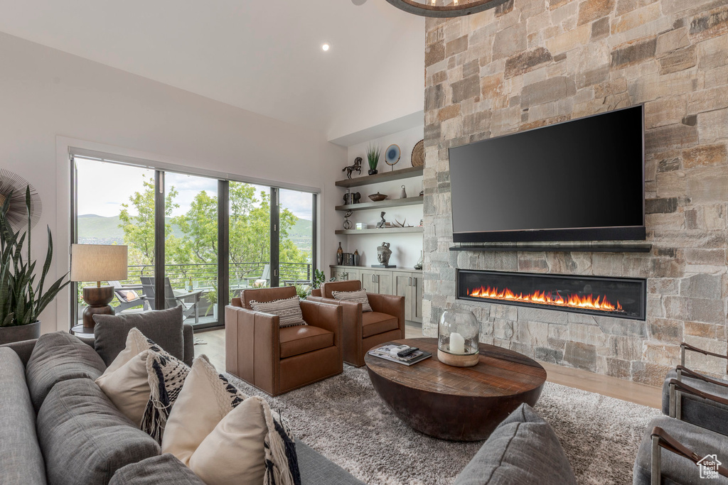 Living room with a fireplace, high vaulted ceiling, and wood finished floors