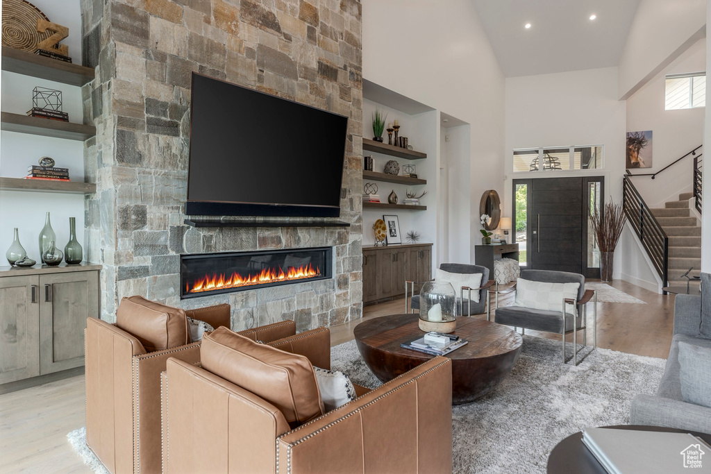 Living area with a fireplace, high vaulted ceiling, wood finished floors, stairs, and built in features