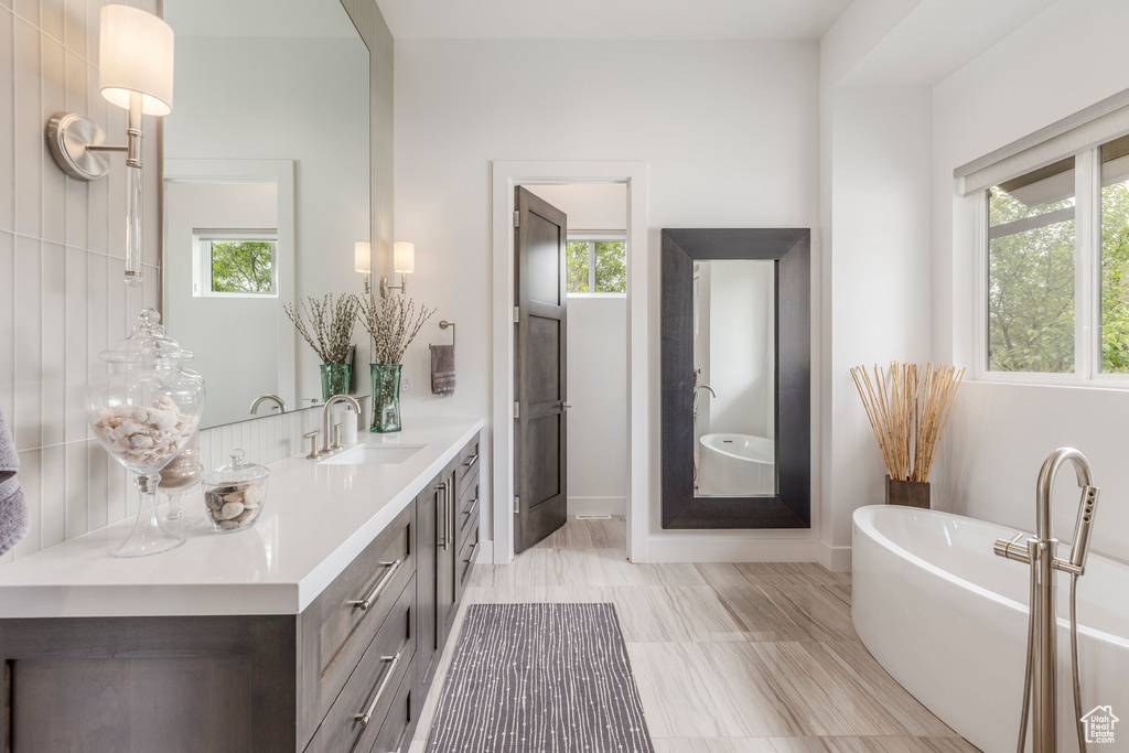 Bathroom featuring vanity, a freestanding tub, and healthy amount of natural light