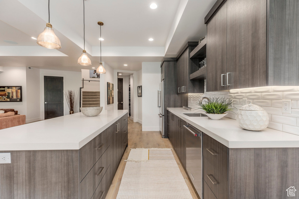 Kitchen with modern cabinets, open shelves, a spacious island, appliances with stainless steel finishes, and a sink
