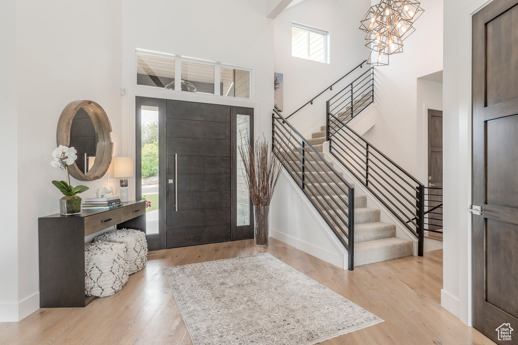 Foyer with a high ceiling, healthy amount of natural light, stairway, and wood finished floors