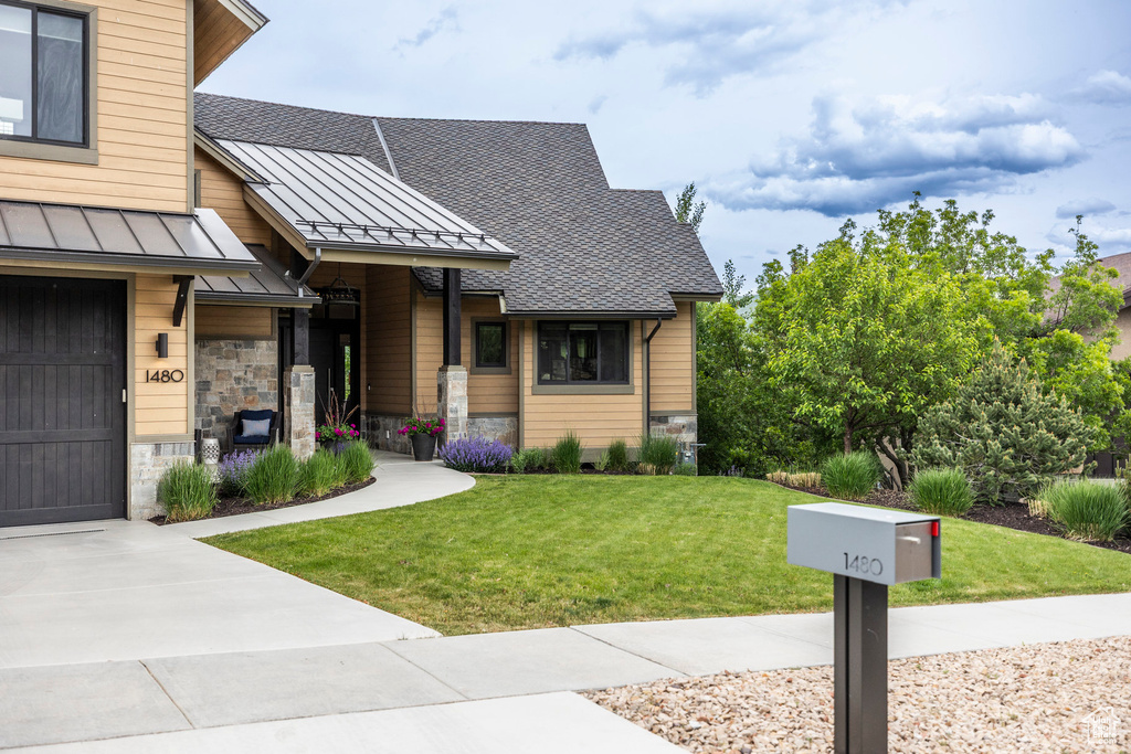 View of front of house featuring a standing seam roof, stone siding, a front lawn, metal roof, and a shingled roof