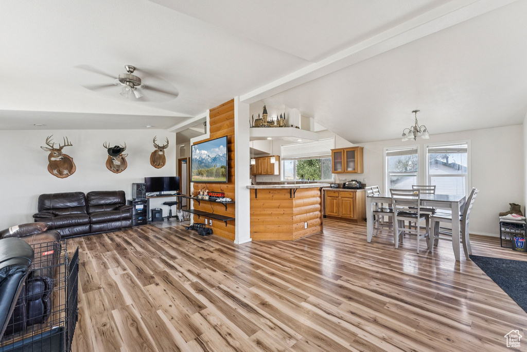 Living room with light wood-type flooring, a chandelier, a ceiling fan, and lofted ceiling