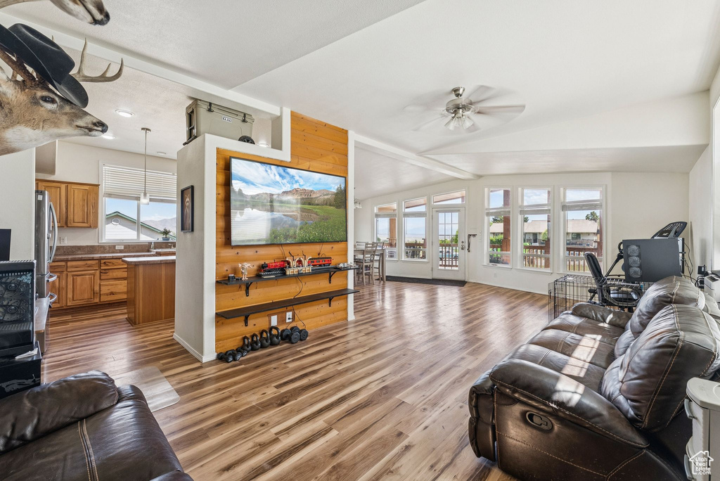 Living room featuring wood finished floors, healthy amount of natural light, ceiling fan, and vaulted ceiling