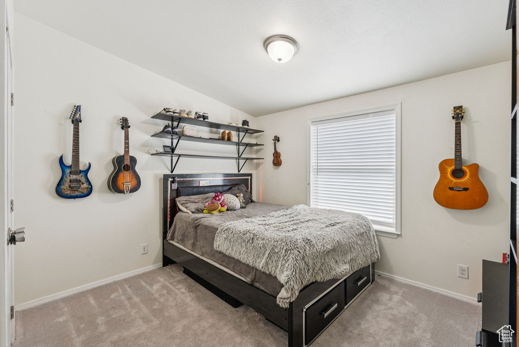 Bedroom with light colored carpet, baseboards, and vaulted ceiling