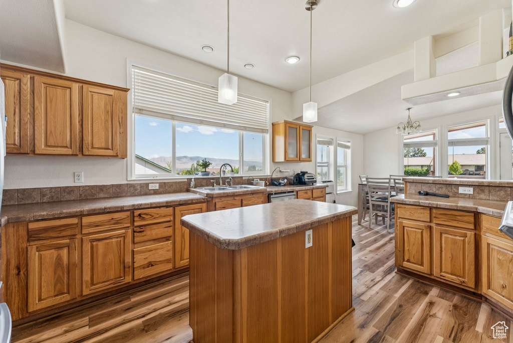 Kitchen with a sink, brown cabinetry, wood finished floors, plenty of natural light, and recessed lighting