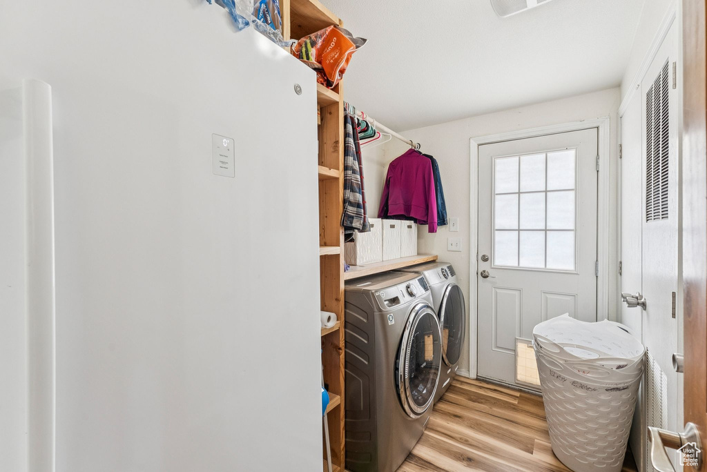 Washroom featuring washing machine and dryer and light wood-style floors