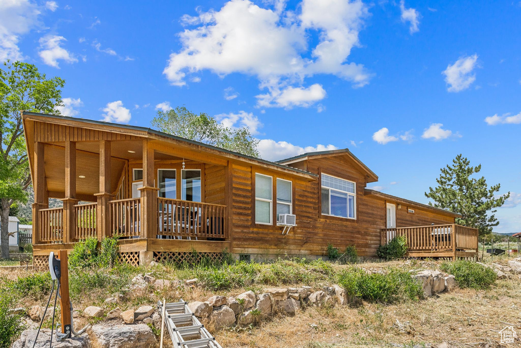 View of front facade featuring crawl space, a wooden deck, and cooling unit