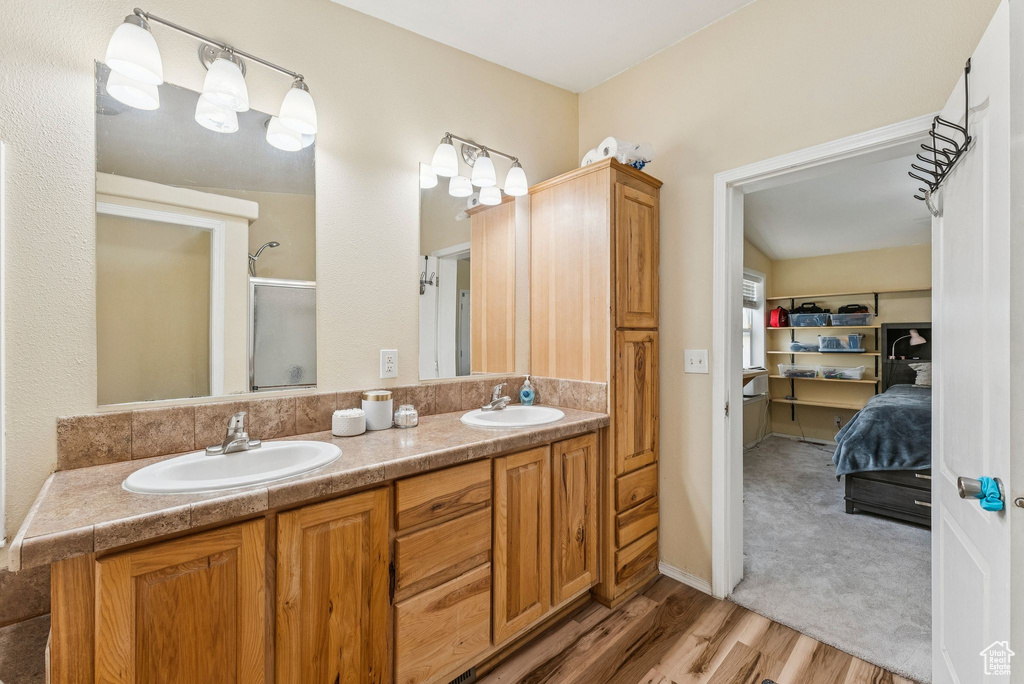 Bathroom featuring wood finished floors, a shower with door, and double vanity