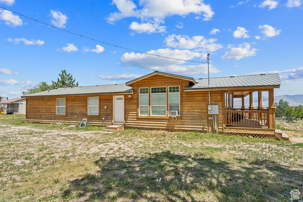 Rear view of property featuring metal roof, a mountain view, and a yard