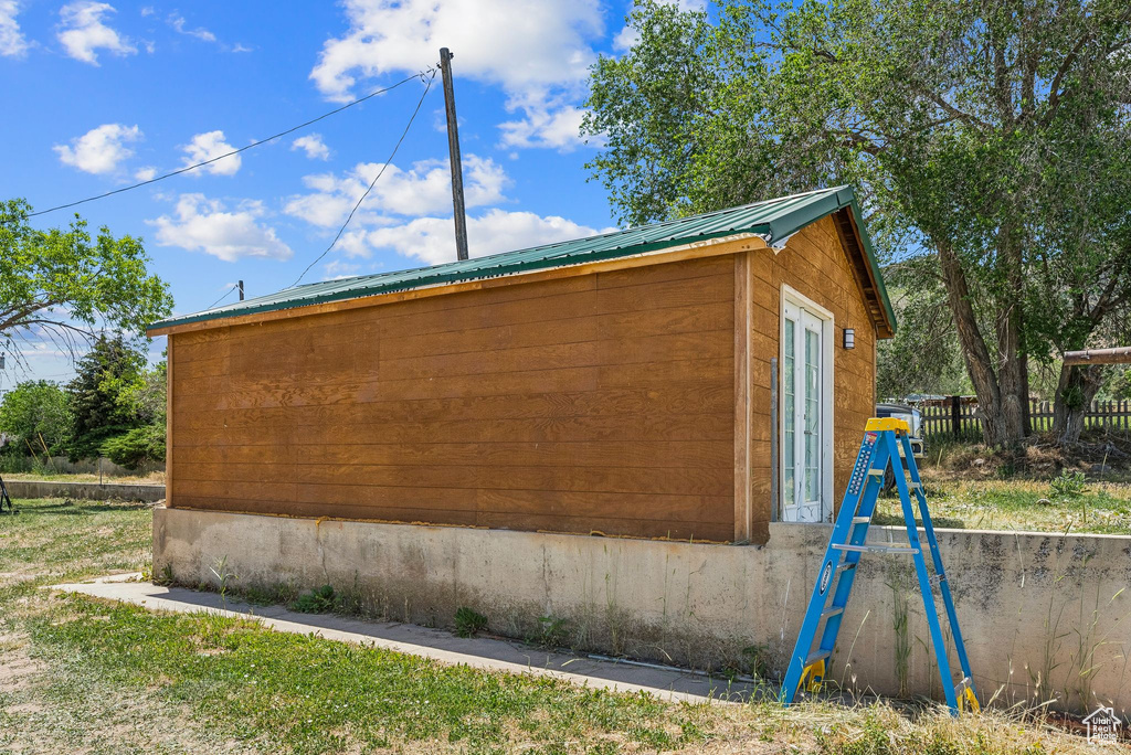 View of property exterior featuring metal roof and an outdoor structure