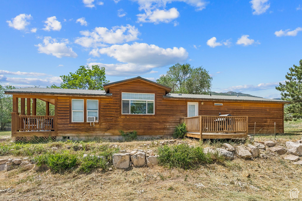 View of front of home with a deck, metal roof, crawl space, and cooling unit