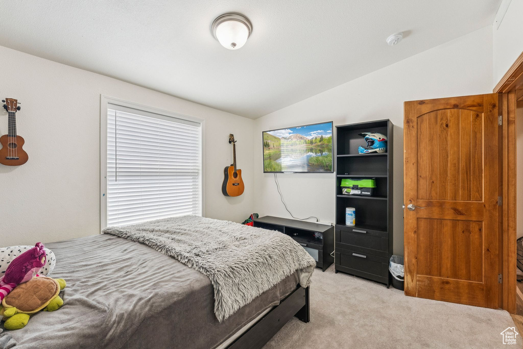 Bedroom featuring vaulted ceiling and light colored carpet