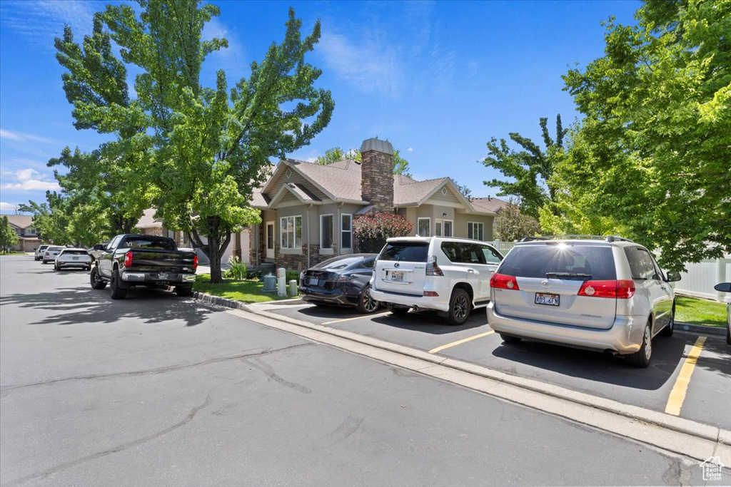 View of property hidden behind natural elements with uncovered parking