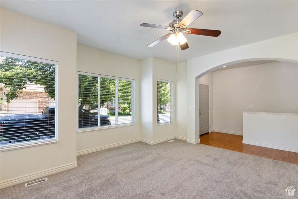 Unfurnished room with carpet, arched walkways, a ceiling fan, and baseboards