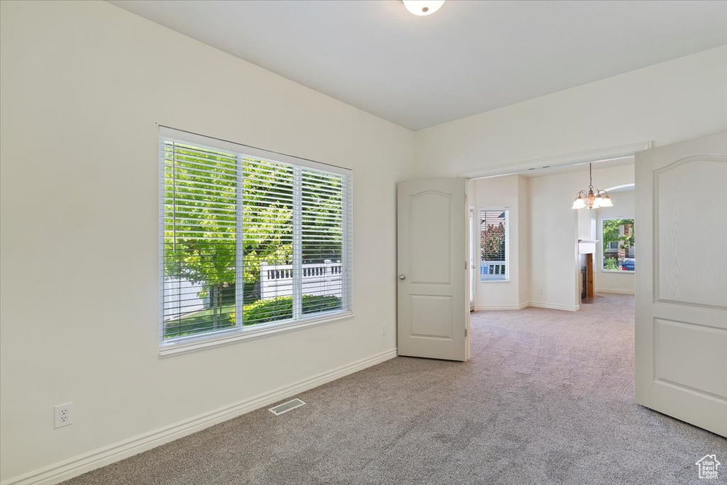 Unfurnished room with a chandelier, carpet floors, healthy amount of natural light, and baseboards