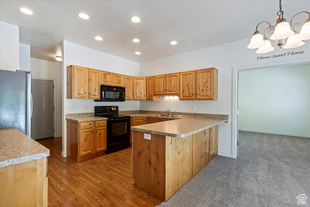 Kitchen featuring black appliances, a sink, a chandelier, recessed lighting, and a peninsula