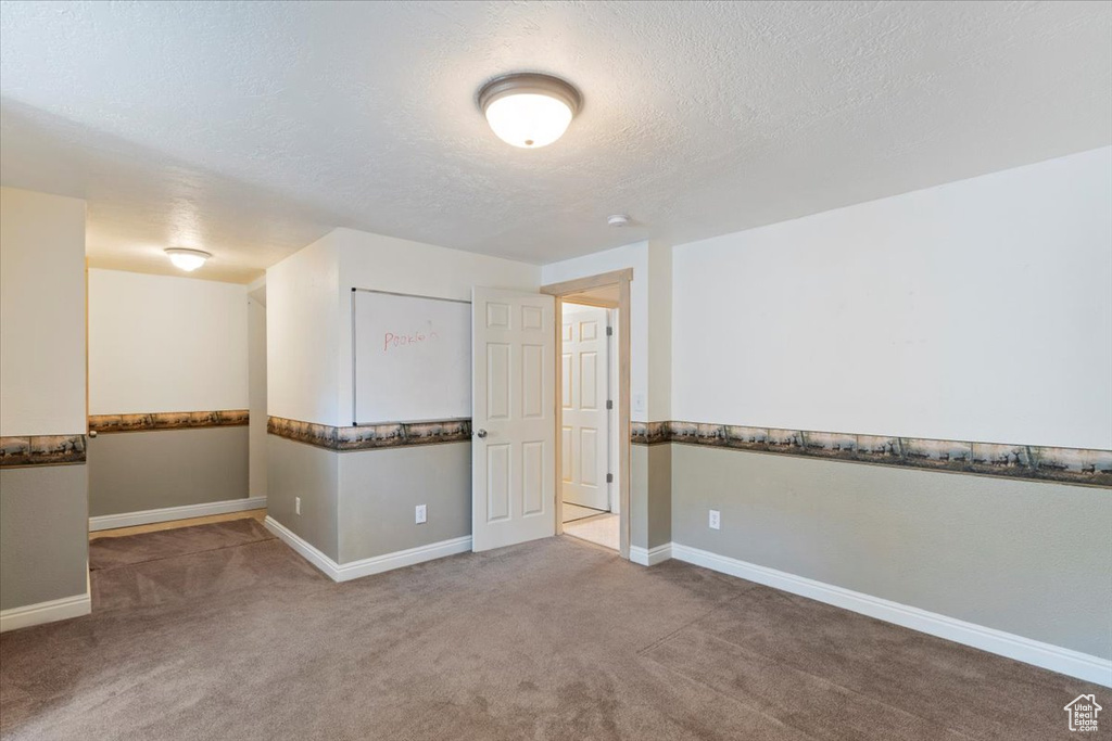Spare room with carpet floors, baseboards, and a textured ceiling