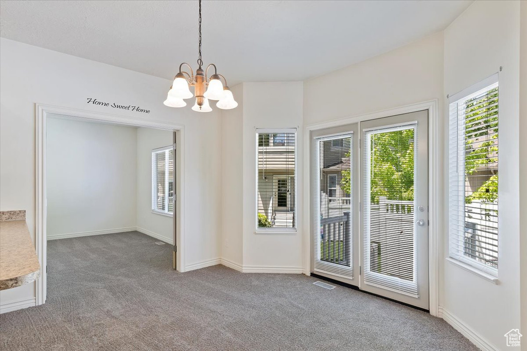 Unfurnished dining area with carpet floors, a chandelier, and baseboards