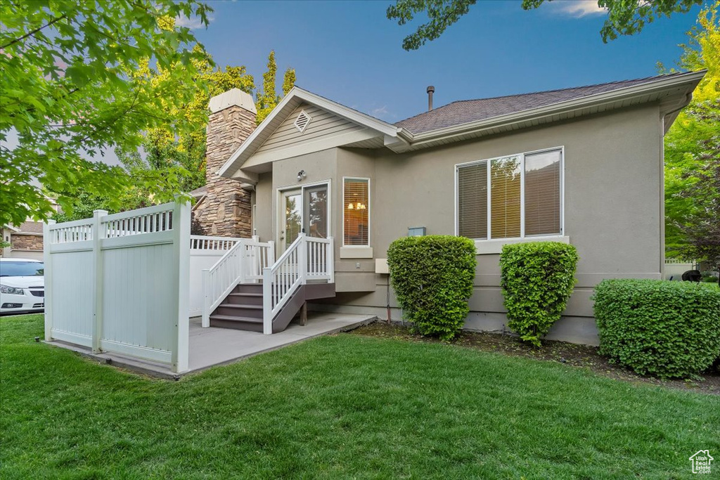 View of front of home featuring a front yard, a chimney, and stucco siding