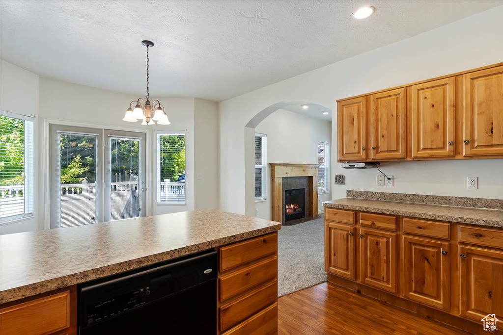 Kitchen featuring black dishwasher, arched walkways, dark wood finished floors, a chandelier, and a fireplace with flush hearth