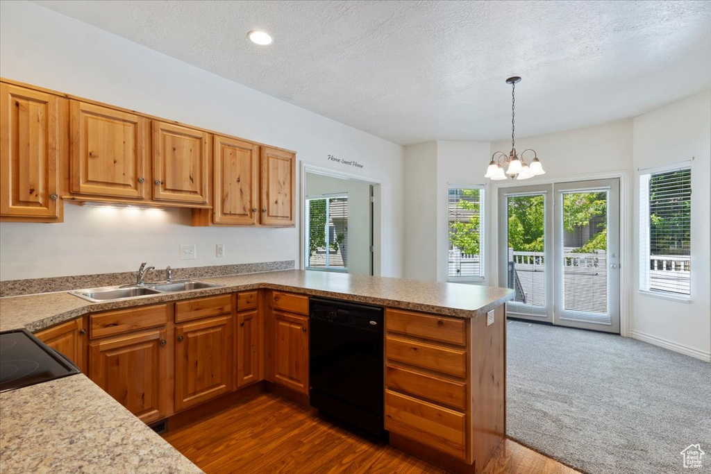 Kitchen featuring black dishwasher, a sink, a peninsula, light countertops, and a chandelier