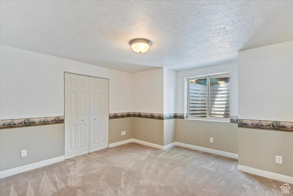 Unfurnished room featuring carpet floors, a textured ceiling, and baseboards