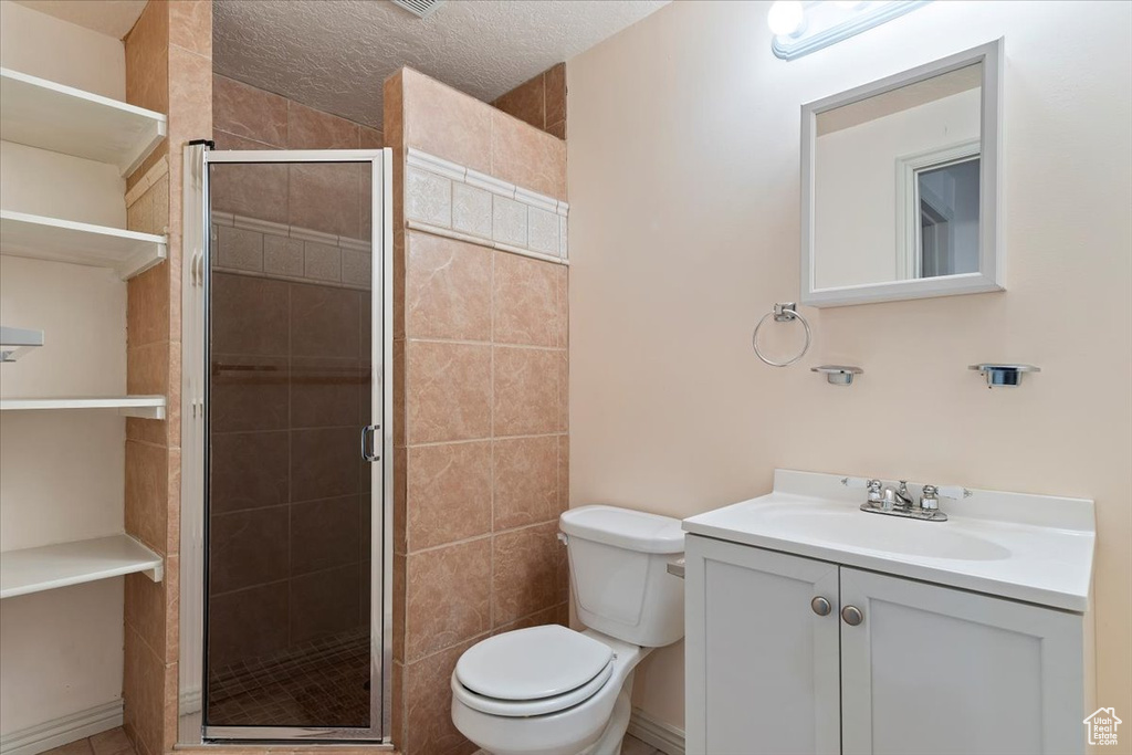 Bathroom with toilet, vanity, a stall shower, and a textured ceiling