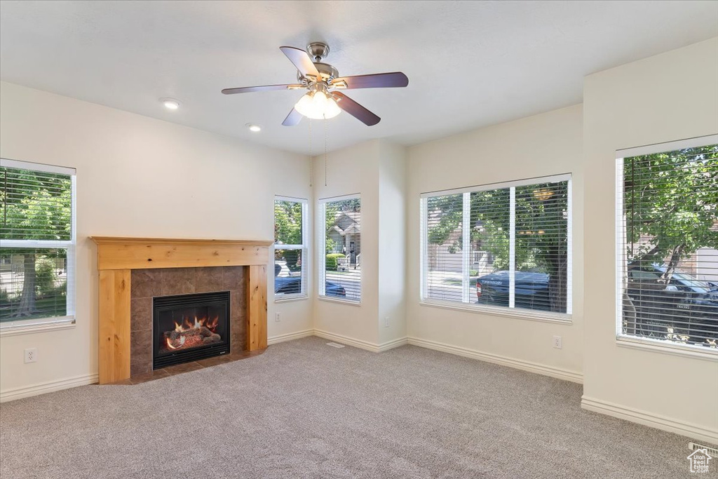 Unfurnished living room with carpet flooring, a fireplace, a ceiling fan, and baseboards