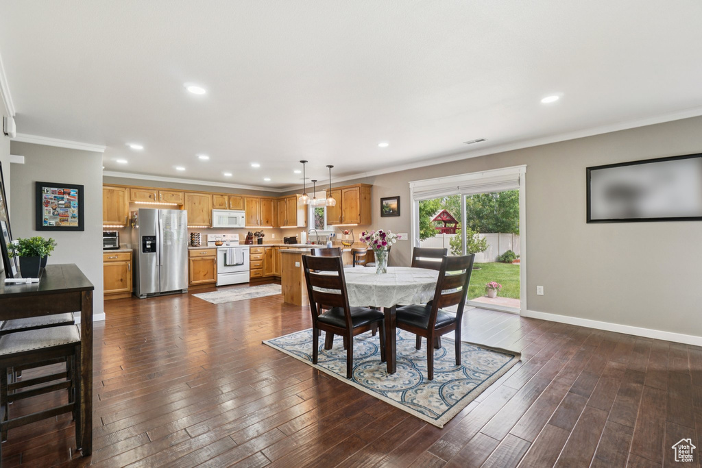 Dining area with ornamental molding, recessed lighting, dark wood finished floors, and baseboards