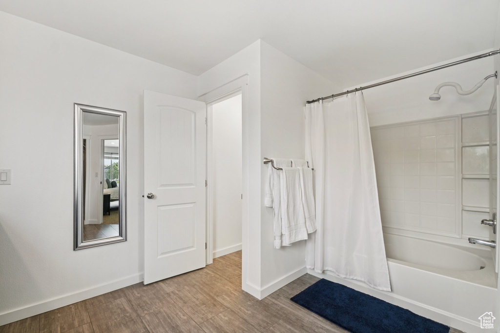 Full bath with shower / bath combo with shower curtain, wood finished floors, and baseboards