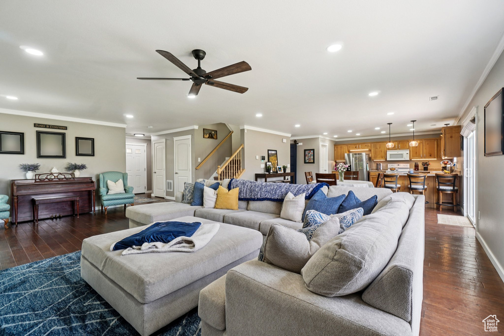 Living area with recessed lighting, stairs, dark wood-style flooring, ornamental molding, and a ceiling fan