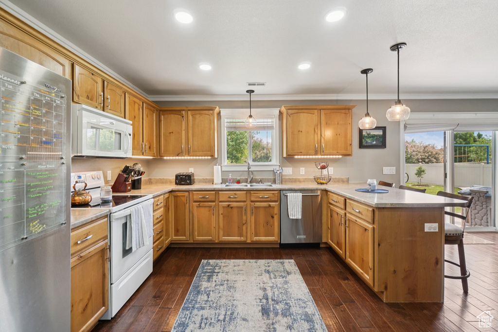 Kitchen featuring stainless steel appliances, a peninsula, light countertops, a sink, and ornamental molding