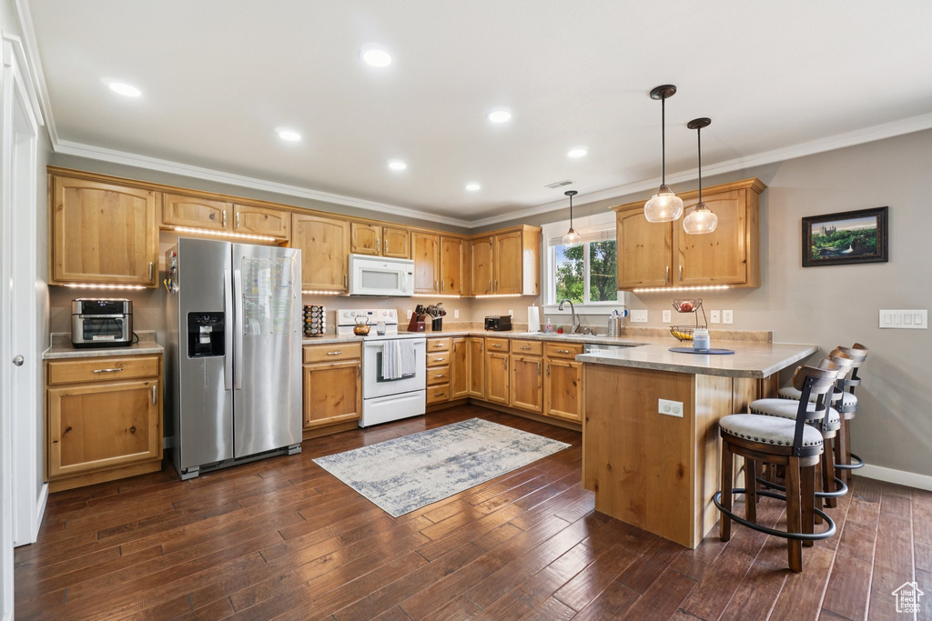 Kitchen with white appliances, a peninsula, crown molding, a kitchen bar, and a sink