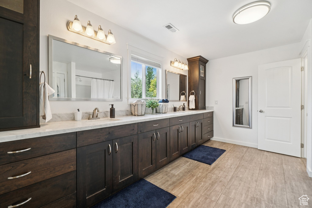 Full bath featuring double vanity, wood finished floors, and a shower with shower curtain