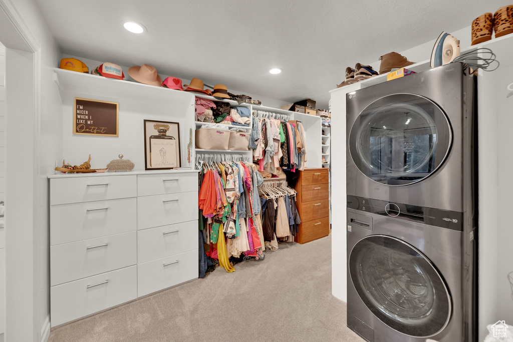 Laundry room with estacked washer and dryer, carpet floors, and recessed lighting