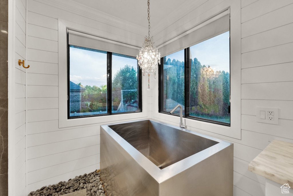 Bathroom with healthy amount of natural light, a chandelier, and ornamental molding