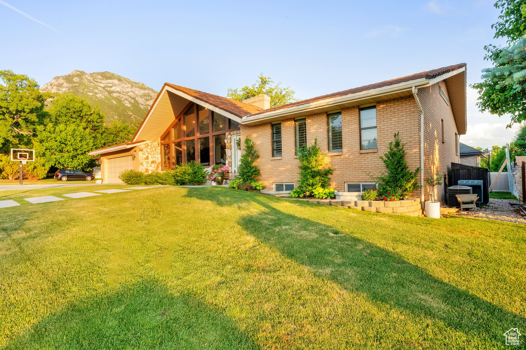 View of front of home featuring brick siding, concrete driveway, an attached garage, a mountain view, and a chimney