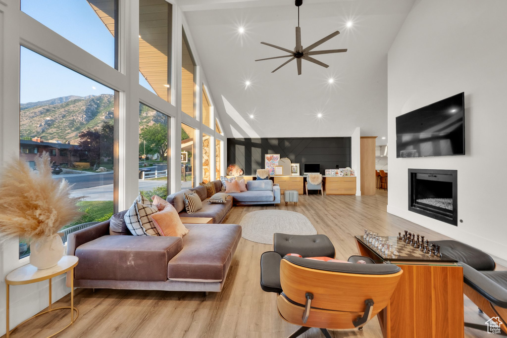 Living area featuring high vaulted ceiling, a fireplace, wood finished floors, a mountain view, and plenty of natural light