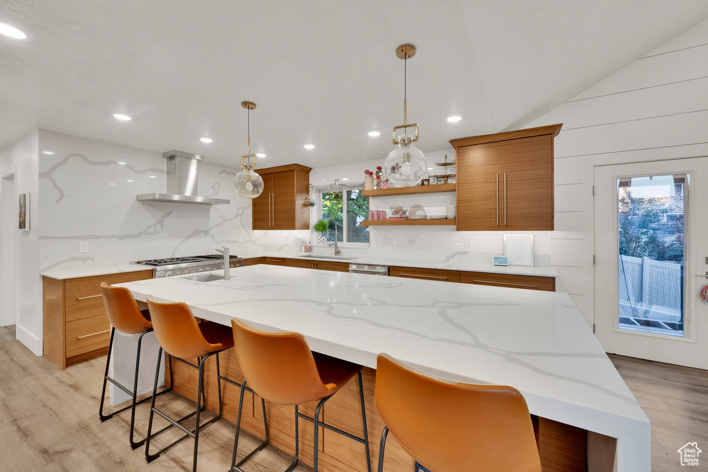 Kitchen with wall chimney exhaust hood, brown cabinets, open shelves, light wood finished floors, and recessed lighting