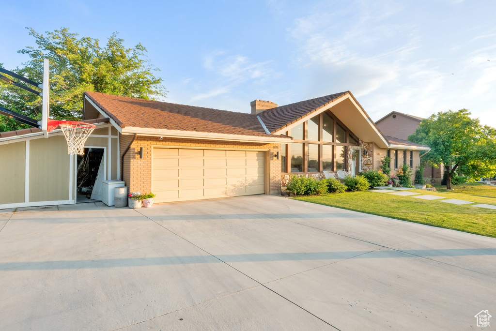 View of front of home with an attached garage, brick siding, a chimney, and concrete driveway