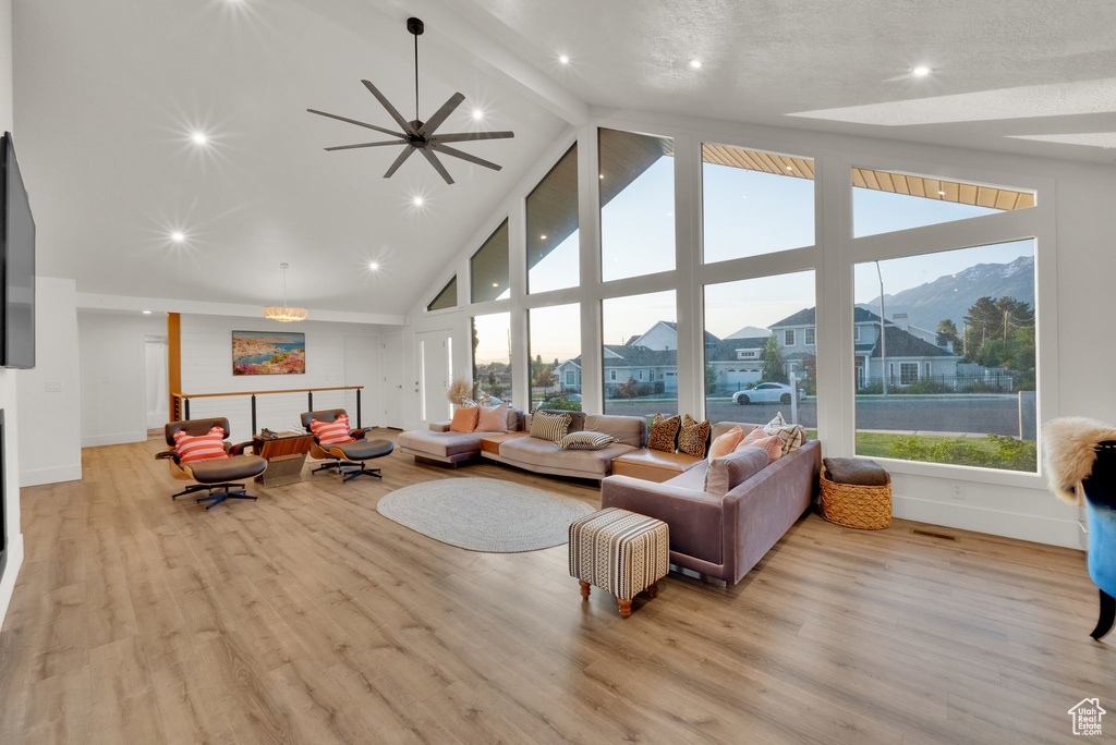 Living room featuring high vaulted ceiling, beamed ceiling, light wood-style floors, and baseboards