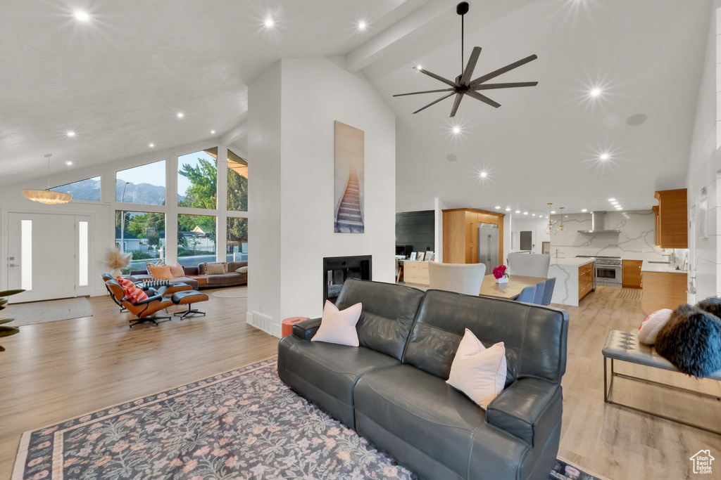 Living area featuring high vaulted ceiling, light wood-type flooring, ceiling fan, recessed lighting, and beam ceiling