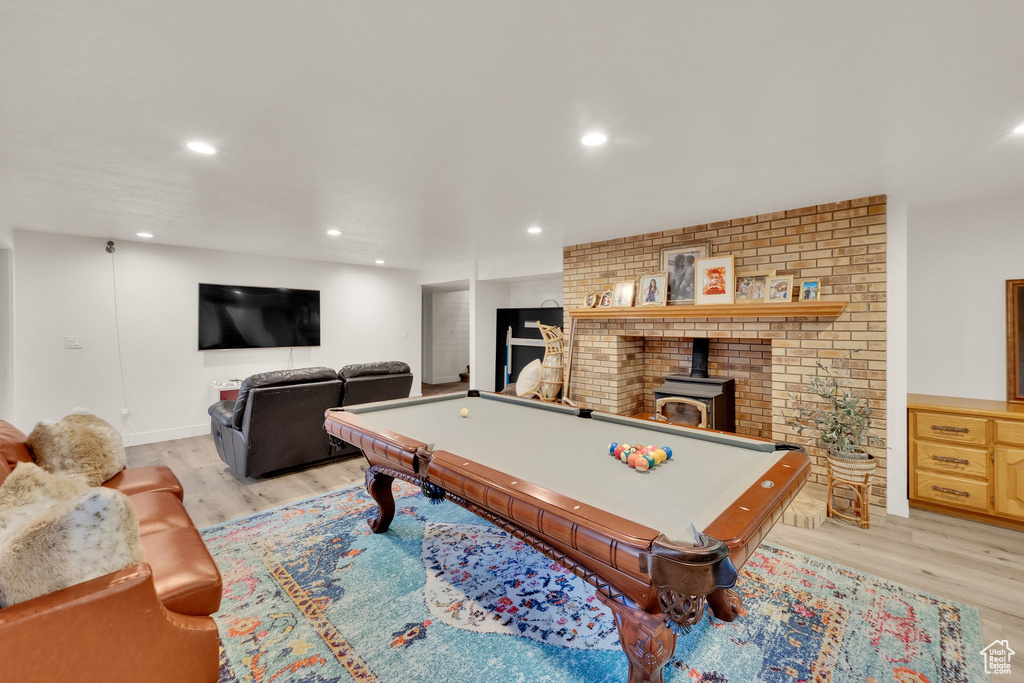 Playroom featuring light wood-style flooring, billiards table, recessed lighting, and a wood stove