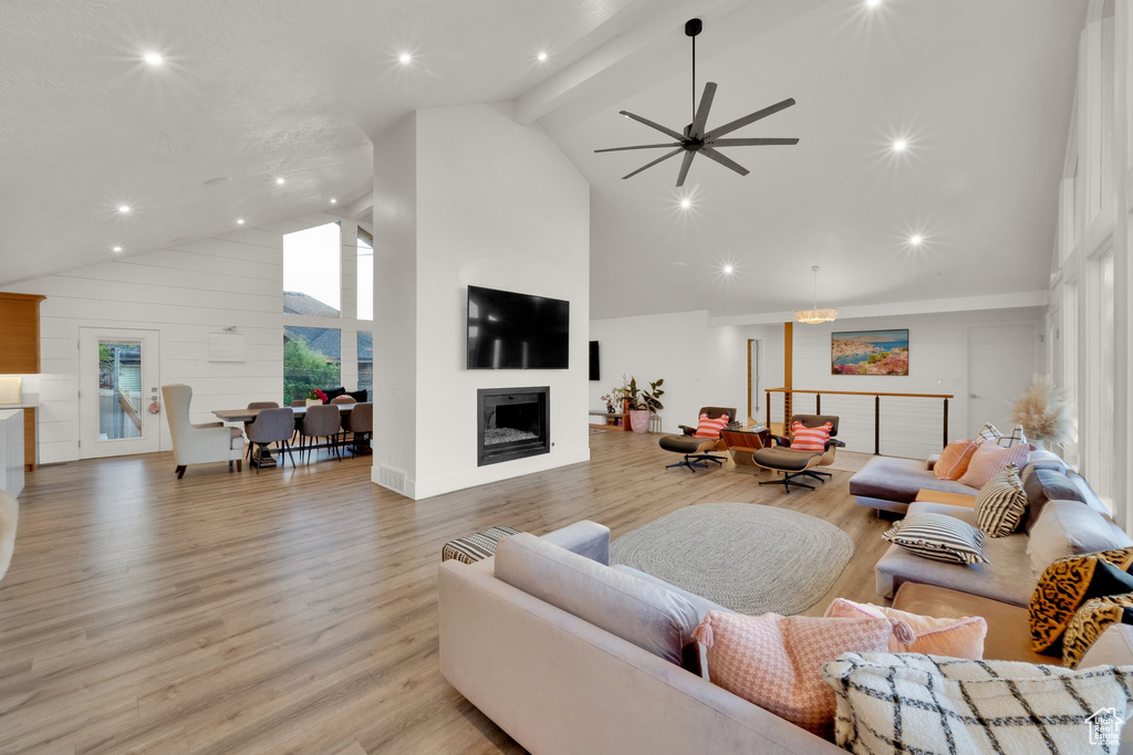 Living room featuring high vaulted ceiling, a fireplace, light wood-style floors, ceiling fan, and recessed lighting