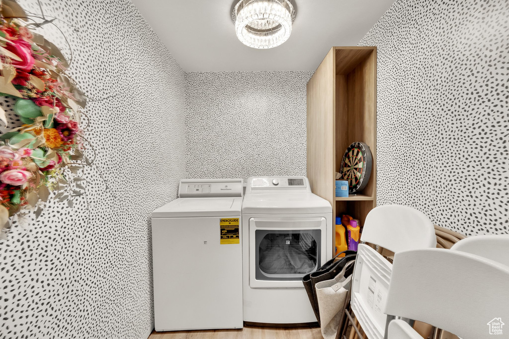 Washroom featuring washer and dryer, a chandelier, and light wood-type flooring